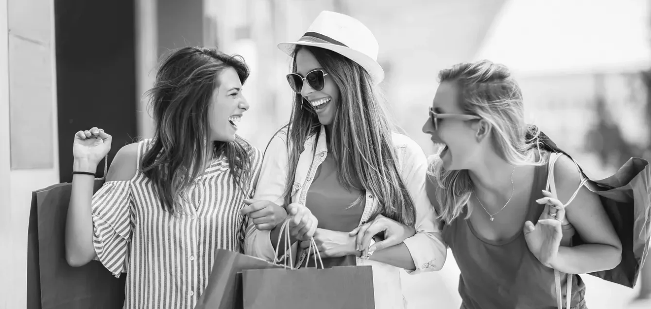 Three happy women carrying shopping bags, representing improved eCommerce conversion through better product discovery and user experience.