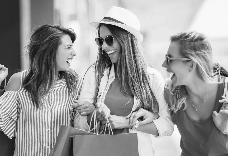 Three happy women carrying shopping bags, representing improved eCommerce conversion through better product discovery and user experience.